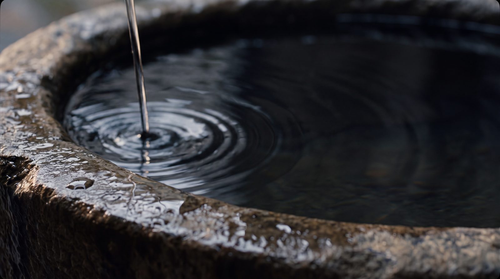 Dunkles, klares Wasser über verwittertem Stein, ein einzelnes hartes Seitenlicht